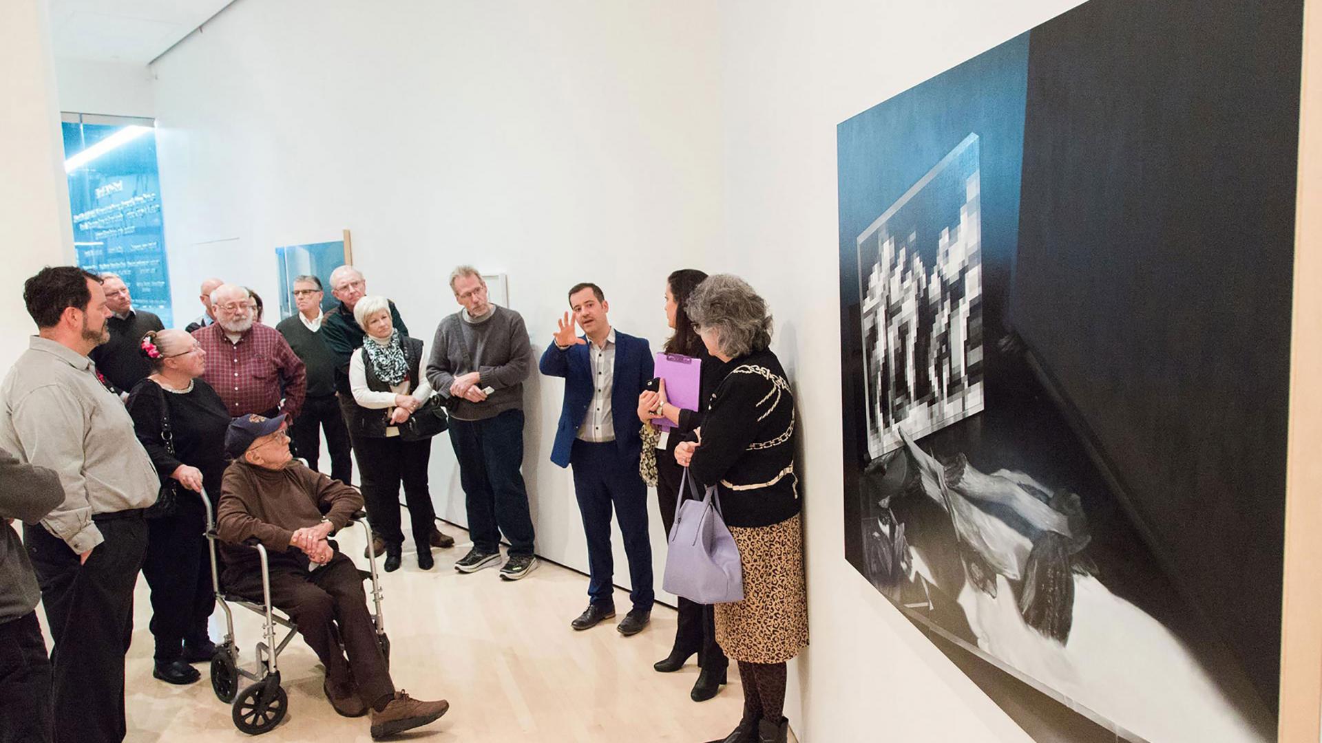 Group of adults listening to a lecture in a gallery