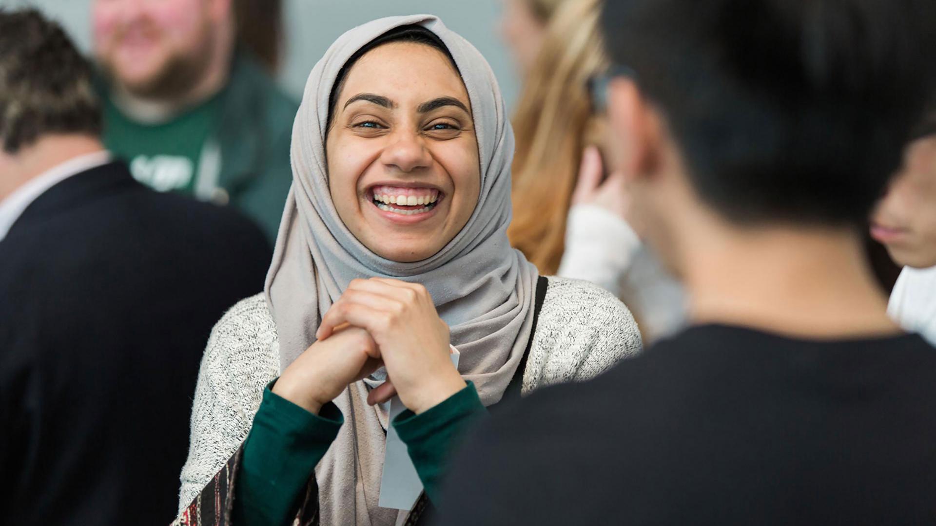 A woman in a head scarf smiling brightly
